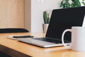 office, desk, coffee cup, laptop and cell phone on top of notebook